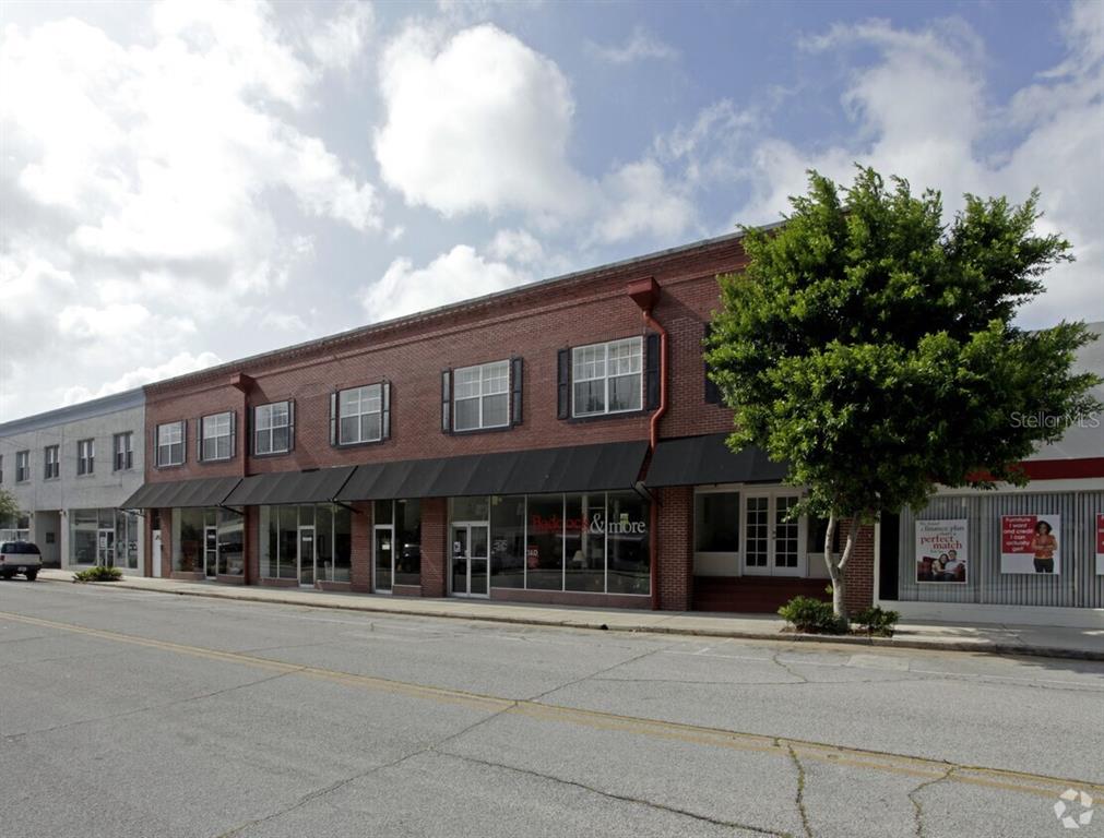 A two-story brick commercial building with black awnings and large storefront windows along the street — 21 MAIN STREET, TITUSVILLE, FL