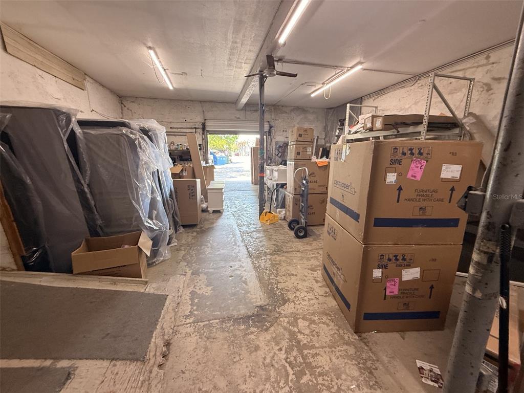 A storage room with concrete floors, fluorescent lighting, and stacked cardboard boxes and furniture — 21 MAIN STREET, TITUSVILLE, FL