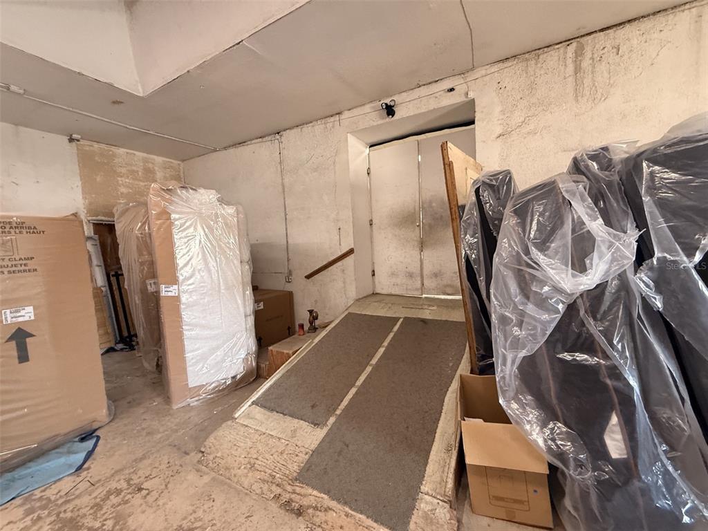 A storage area features a concrete ramp leading to double doors and packed furniture — 21 MAIN STREET, TITUSVILLE, FL