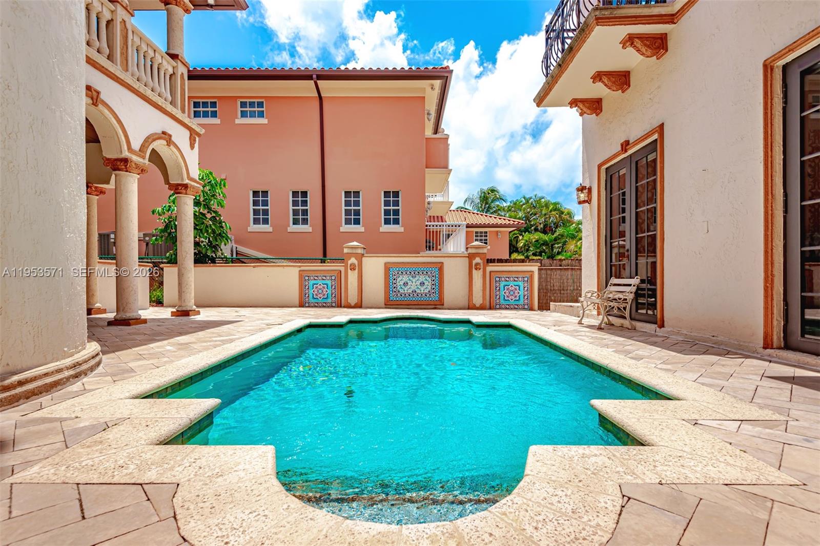 A swimming pool sits in a courtyard between two buildings with tiled patio flooring — 674 Ocean Blvd, Golden Beach FL 33160, GOLDEN BEACH, FL