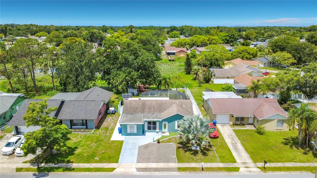 An aerial view shows three suburban houses with driveways and lawns on a sunny day — 3229 COVINA STREET, NEW PORT RICHEY, FL