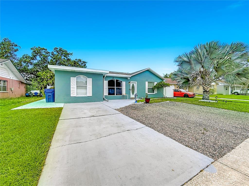 A teal single-story house features a concrete driveway, a gravel yard, and a palm tree — 3229 COVINA STREET, NEW PORT RICHEY, FL