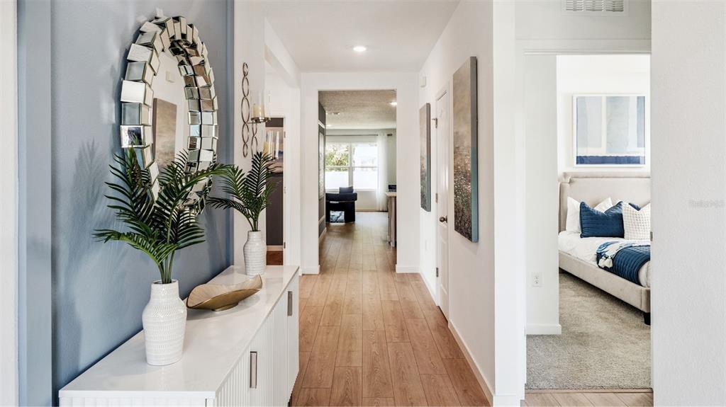 A hallway with wood-look tile flooring leads to a living area past a bedroom entrance — 3285 EASTGROVE TER, SANFORD, FL