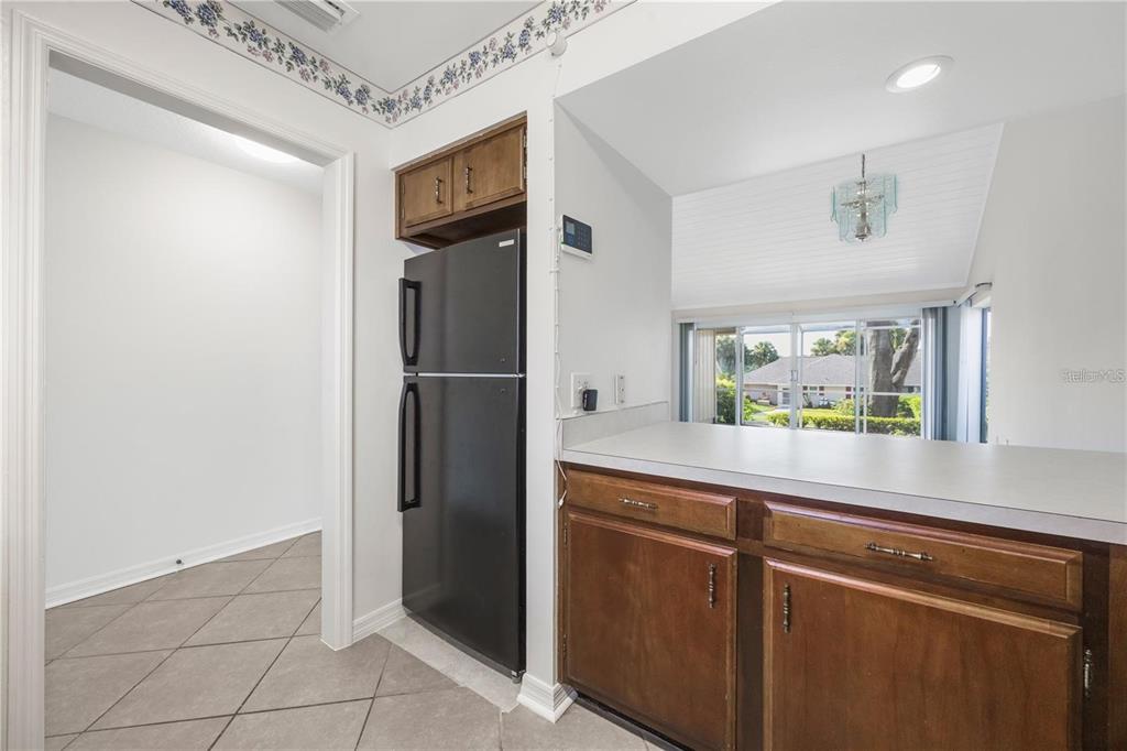 A kitchen features a black refrigerator, wood cabinets, a breakfast bar, and a tiled floor — 1134 VILLA LANE UNIT 95, APOPKA, FL