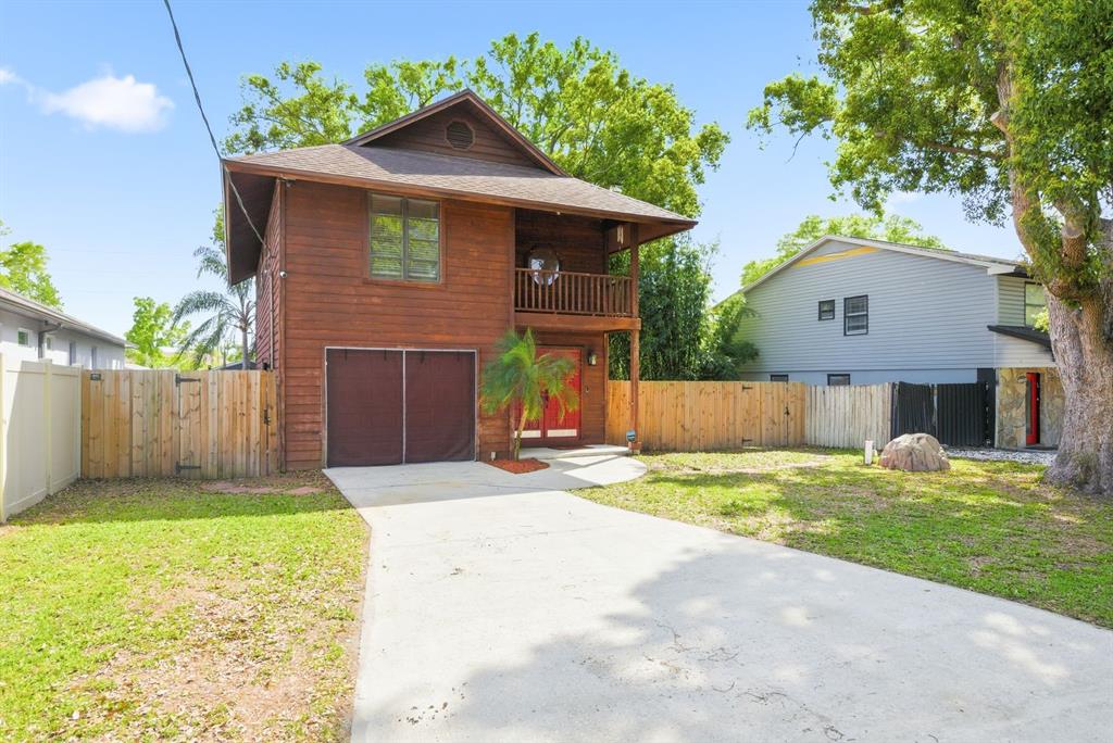 A two-story wooden house with a concrete driveway, a balcony, and a fenced yard — 2204 HOWARD LANE, TAMPA, FL