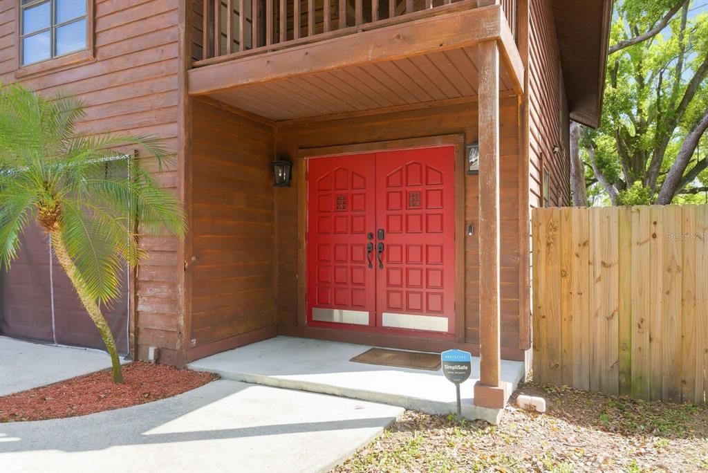 A wooden house exterior features a bright red double front door and a palm tree — 2204 HOWARD LANE, TAMPA, FL