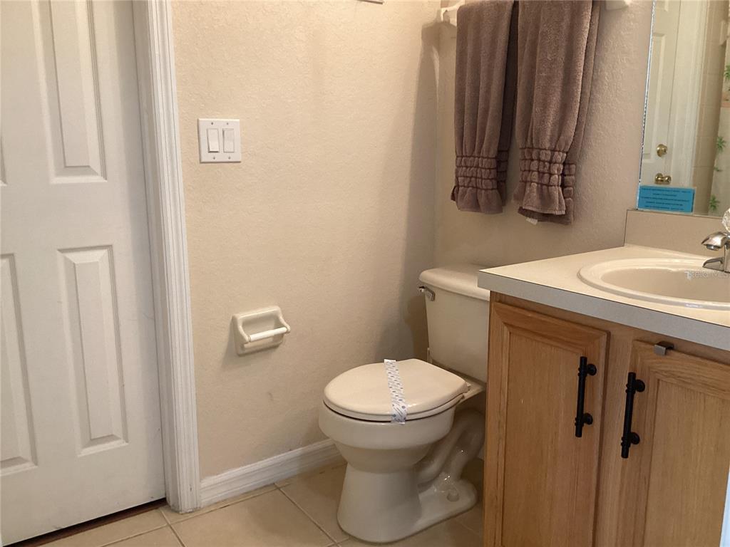 A bathroom features a light wood vanity, a white toilet, and a beige wall — 624 TERRA LAGO STREET, DAVENPORT, FL