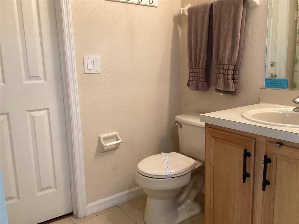 A bathroom features a white toilet, a light wood vanity, and brown towels on a rack — 624 TERRA LAGO STREET, DAVENPORT, FL
