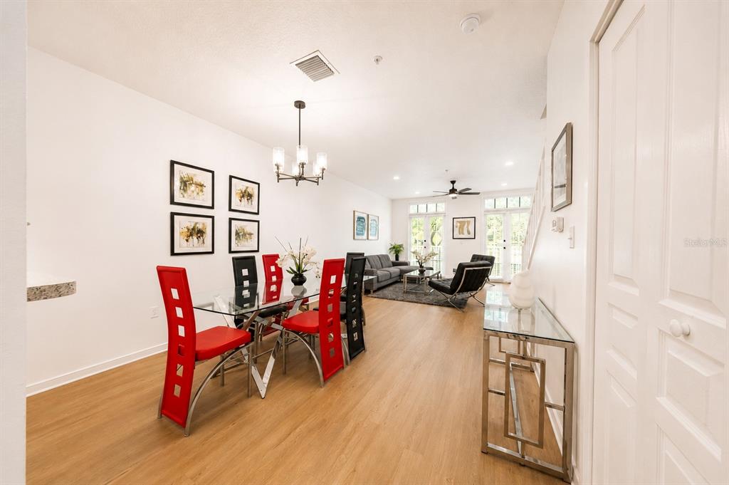 A dining area with red chairs leads into a living room with light wood flooring — 660 CELEBRATION AVENUE UNIT 240, KISSIMMEE, FL