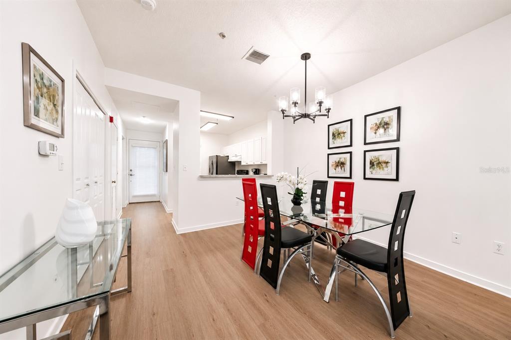A dining area with a glass table, black and red chairs, and a chandelier — 660 CELEBRATION AVENUE UNIT 240, KISSIMMEE, FL
