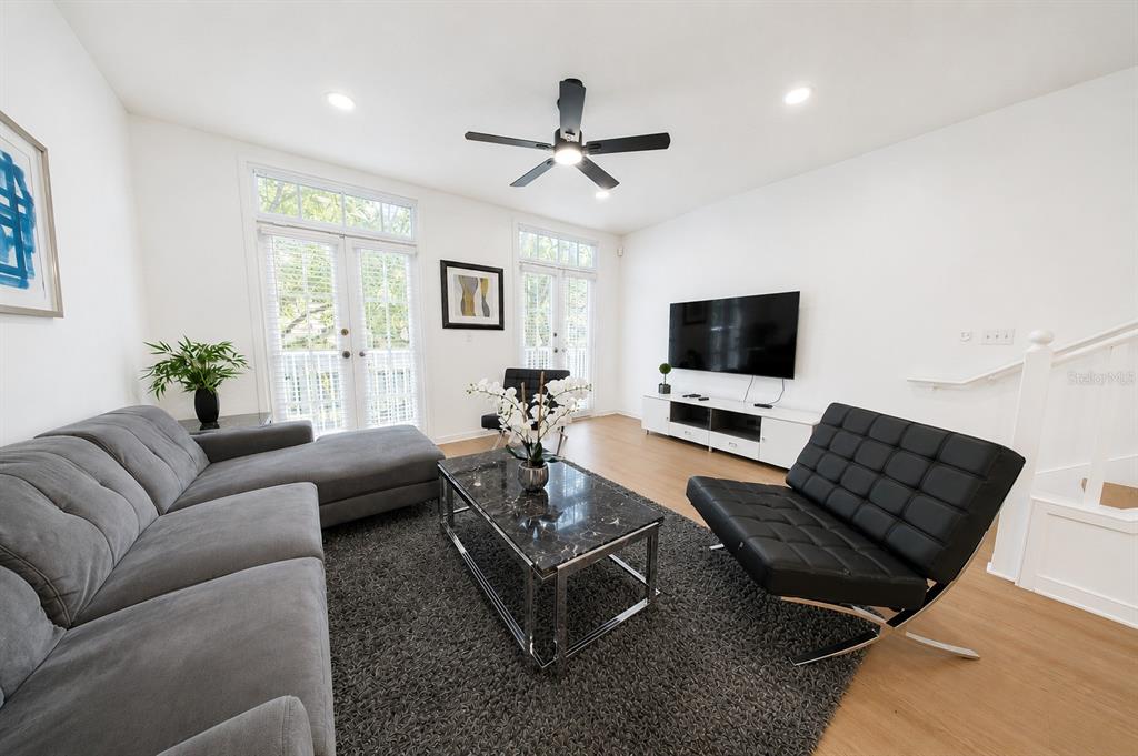 A living room features a grey sectional sofa, black accent chair, coffee table, and television — 660 CELEBRATION AVENUE UNIT 240, KISSIMMEE, FL