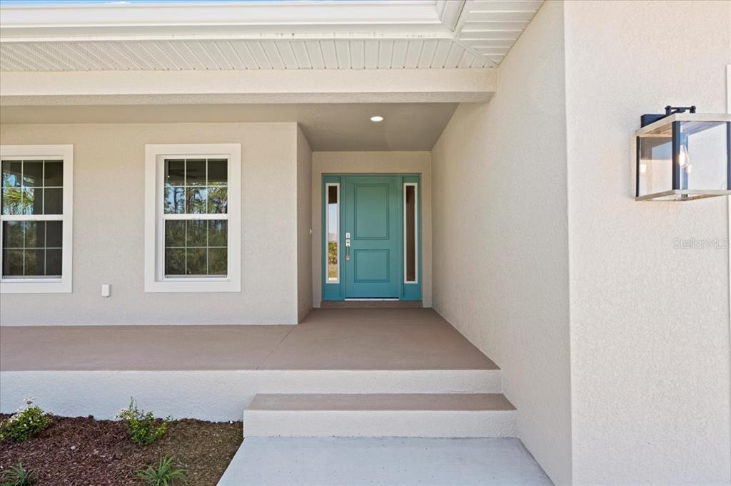 A teal front door is centered on a covered porch with two steps — 109 BEAU RIVAGE DRIVE, ROTONDA WEST, FL