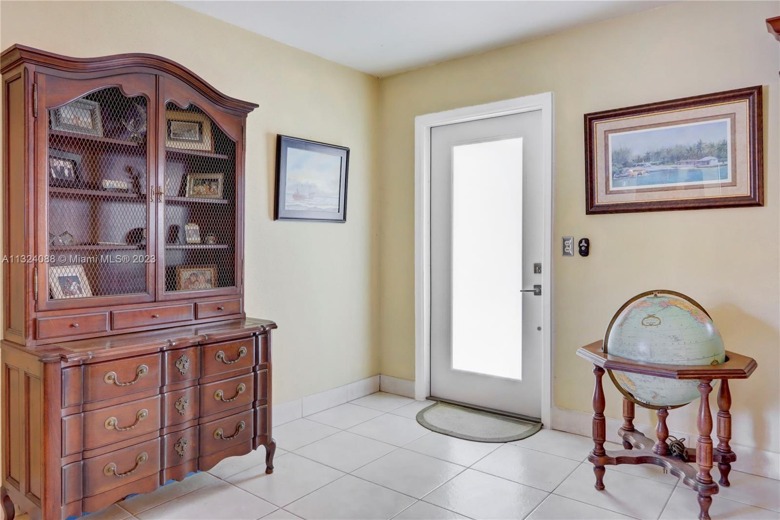 An entryway features a wooden hutch, a globe on a stand, and a glass-paneled door — 694 Brittany Park # O, Delray Beach FL 33446, DELRAY BEACH, FL