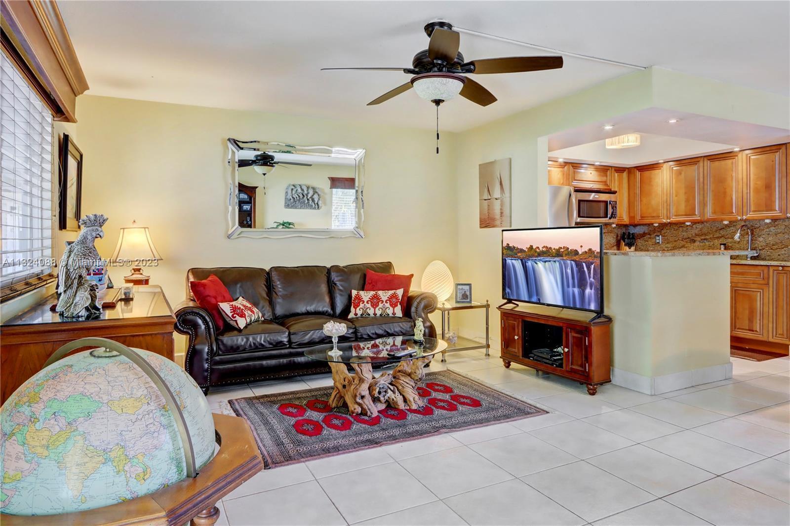 A living room features a leather sofa, a glass coffee table, and an open kitchen — 694 Brittany Park # O, Delray Beach FL 33446, DELRAY BEACH, FL