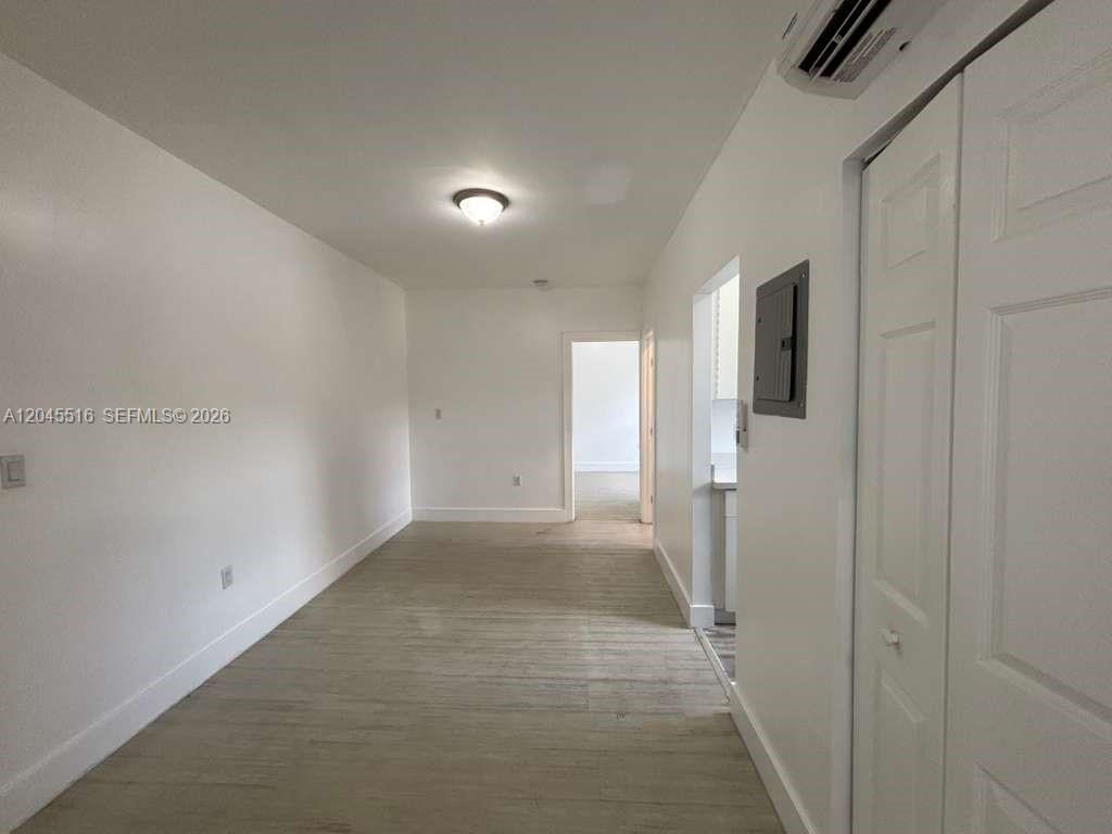 A hallway with light wood-look flooring leads to a doorway and a white closet — 1051 NW 2nd St # 10, Miami FL 33128, MIAMI, FL