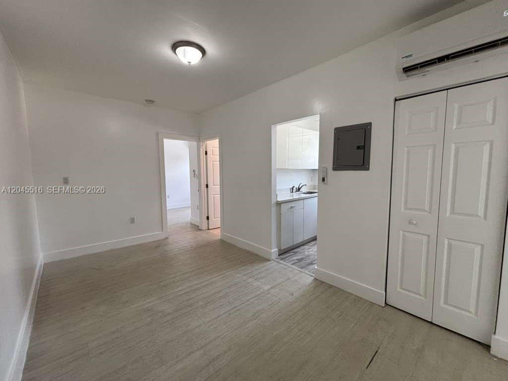 A bright room features light-colored flooring, white walls, a closet, and an open kitchen doorway — 1051 NW 2nd St # 10, Miami FL 33128, MIAMI, FL