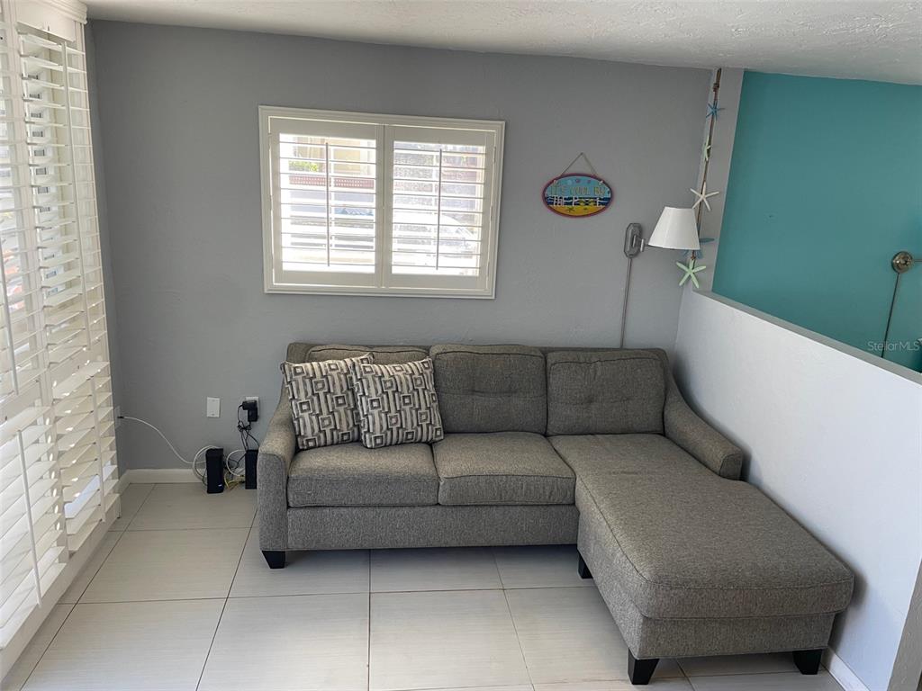 A gray sectional sofa sits against a wall with a window and blue accent wall — 800 BAYWAY BOULEVARD UNIT 14, CLEARWATER BEACH, FL