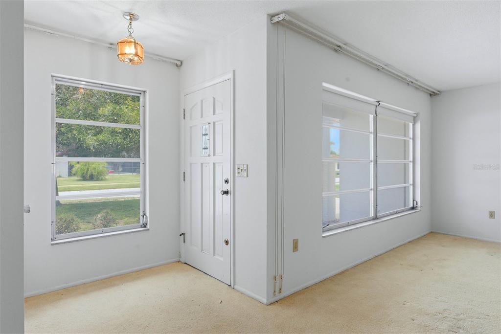 An interior view of a room with white walls, carpeted flooring, and two large windows — 7005 ANTIGUA PLACE, SARASOTA, FL