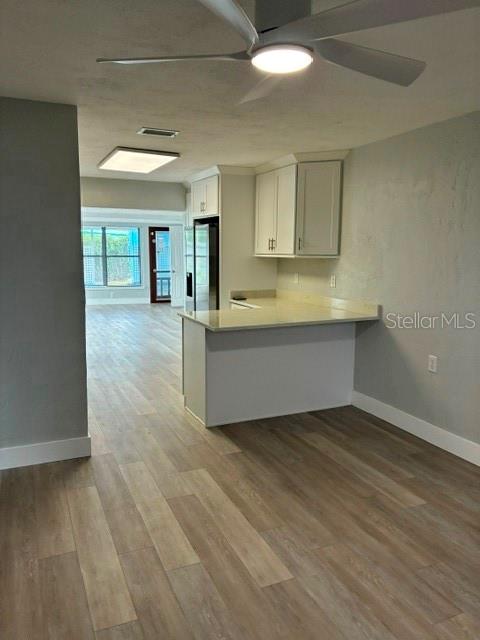 A kitchen with white cabinets and a breakfast bar overlooks a room with wood flooring — 28 AZALEA DRIVE, ORMOND BEACH, FL