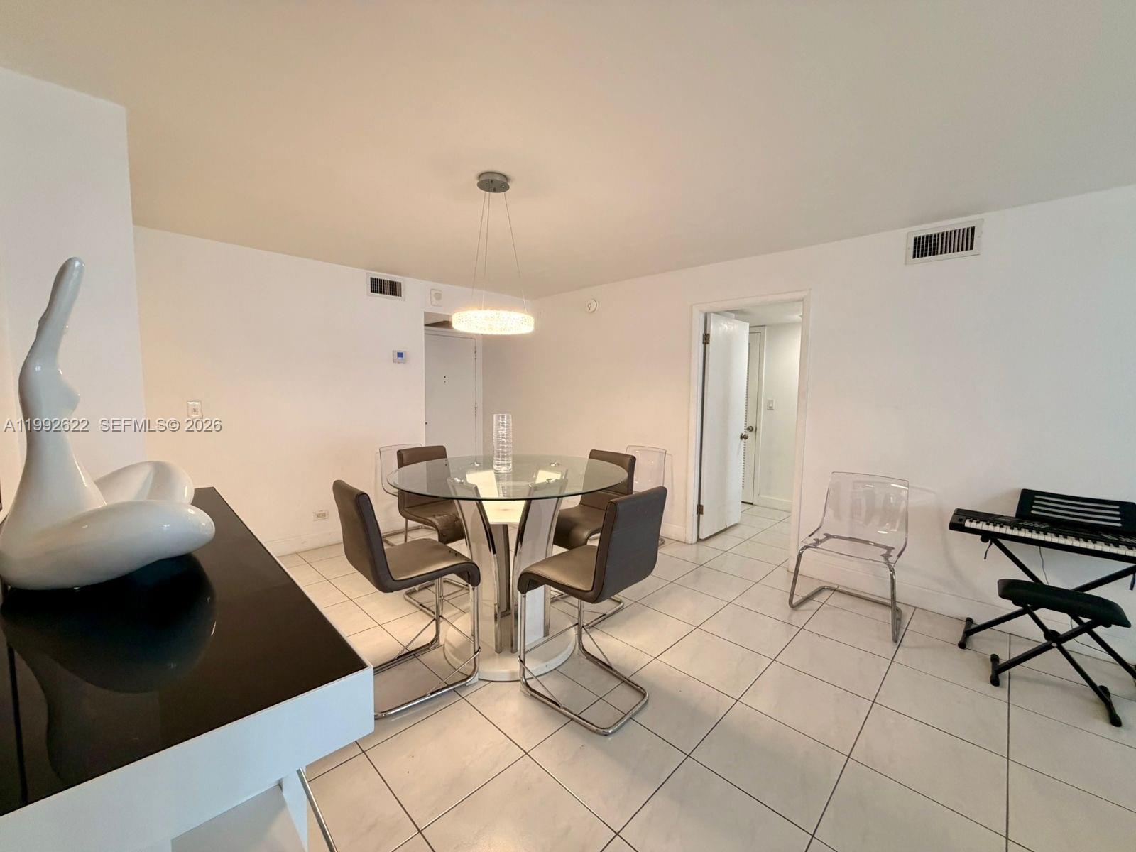 A dining area features a glass-topped table, four chairs, a pendant light, and tile flooring — 6039 Collins Ave # 1506, Miami Beach FL 33140, MIAMI BEACH, FL