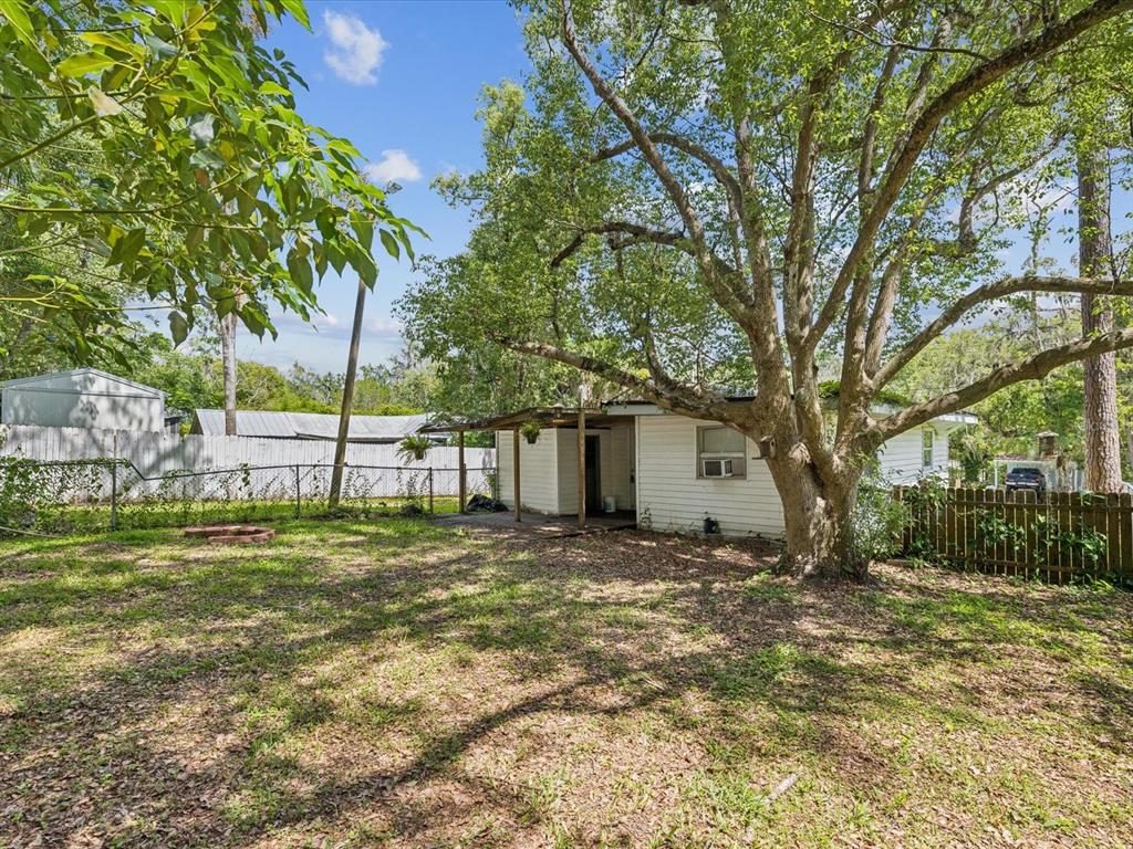 A white house with a covered porch sits in a grassy yard under a large tree — 111 E EARLY STREET, BROOKSVILLE, FL