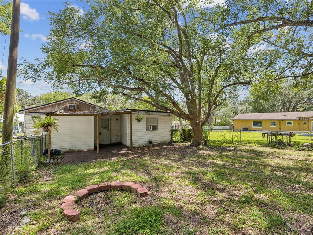 A white house with a covered patio sits in a yard with a large tree — 111 E EARLY STREET, BROOKSVILLE, FL