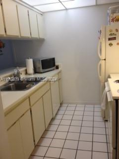 A galley kitchen features white cabinets, a stainless steel sink, a microwave, and tiled flooring — 8160 Geneva Ct # 206, Doral FL 33166, DORAL, FL