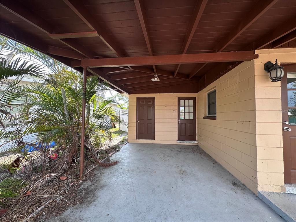 A covered concrete patio features two brown doors and a light-colored block wall exterior — 11452 104TH STREET, LARGO, FL