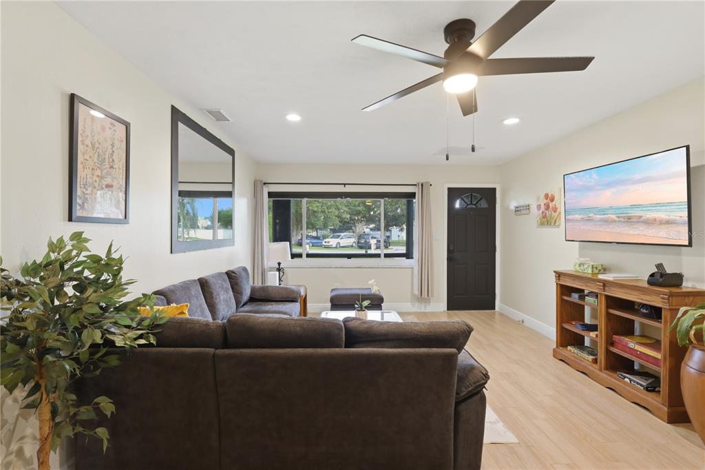 A living room features a dark sectional sofa, a television, and a ceiling fan — 2341 DEVON COURT, WINTER PARK, FL