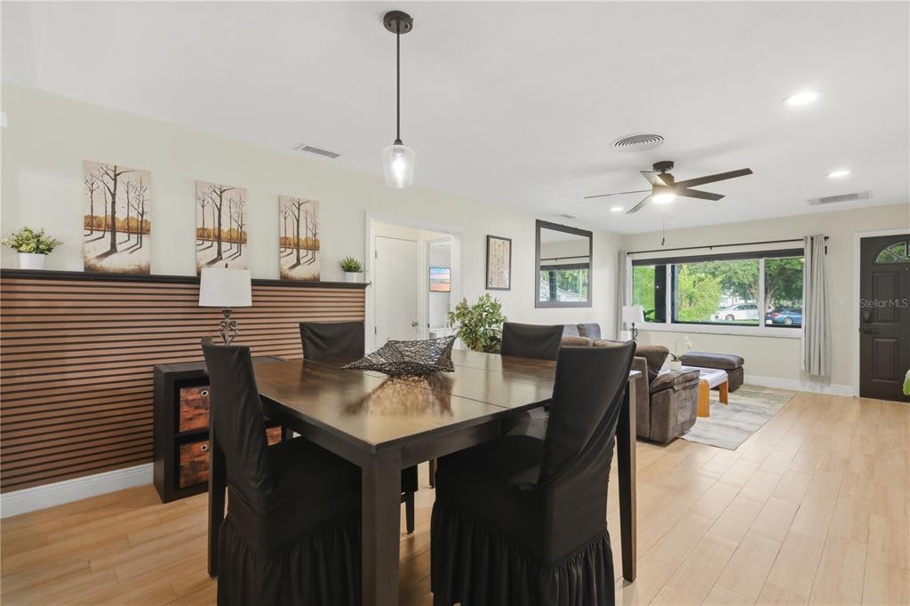 A dining area with a wood-slat accent wall opens into a living room with tile flooring — 2341 DEVON COURT, WINTER PARK, FL