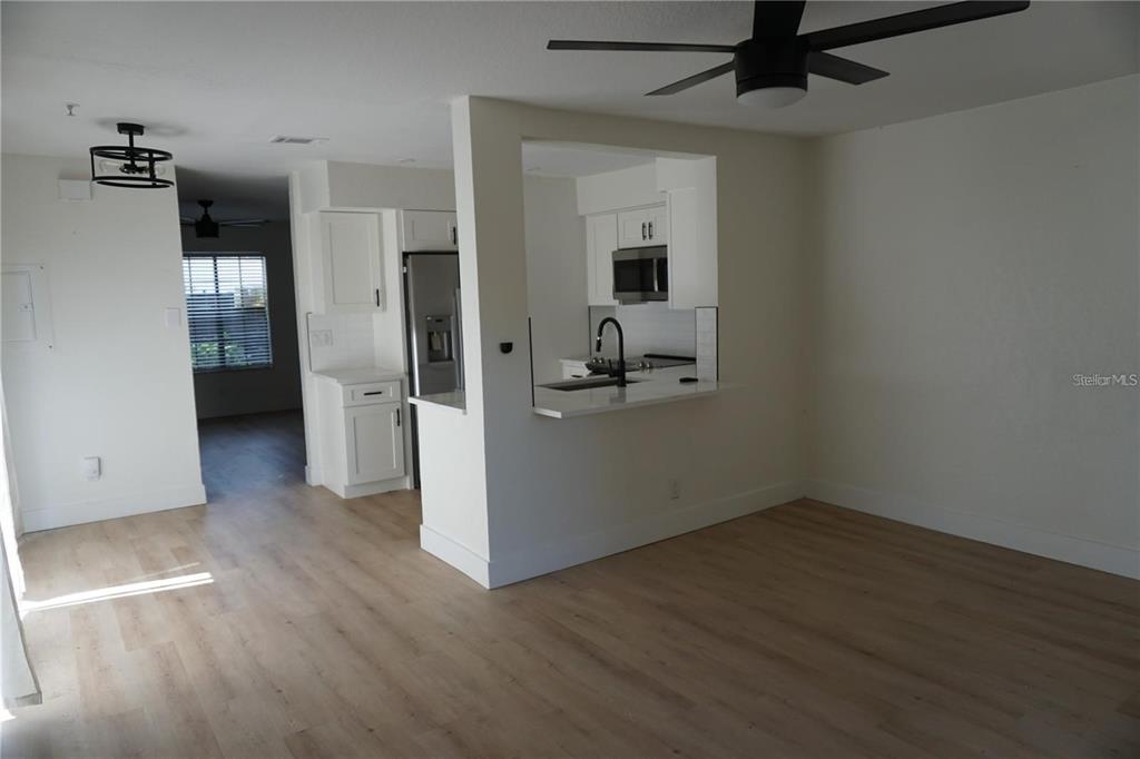 A kitchen with white cabinets and a breakfast bar opens into a living area — 2404 BRIGADOON DRIVE, CLEARWATER, FL
