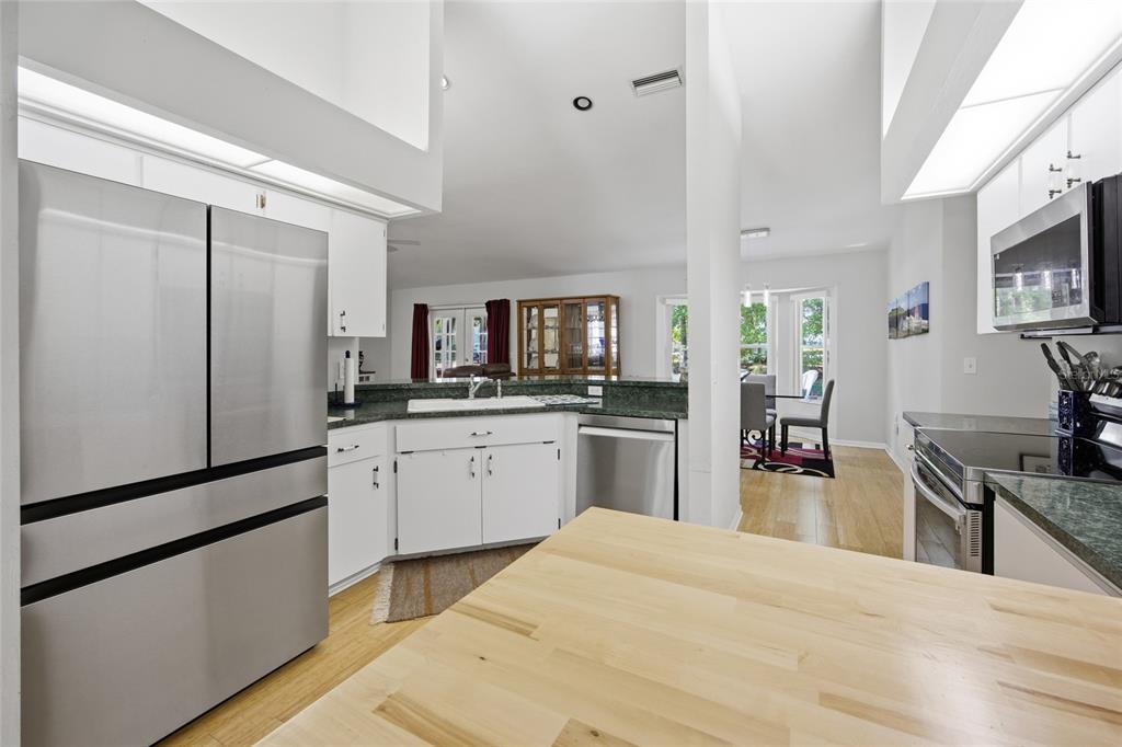A kitchen with white cabinets, stainless steel appliances, and a light wood countertop island — 1106 NW 101ST DRIVE, GAINESVILLE, FL