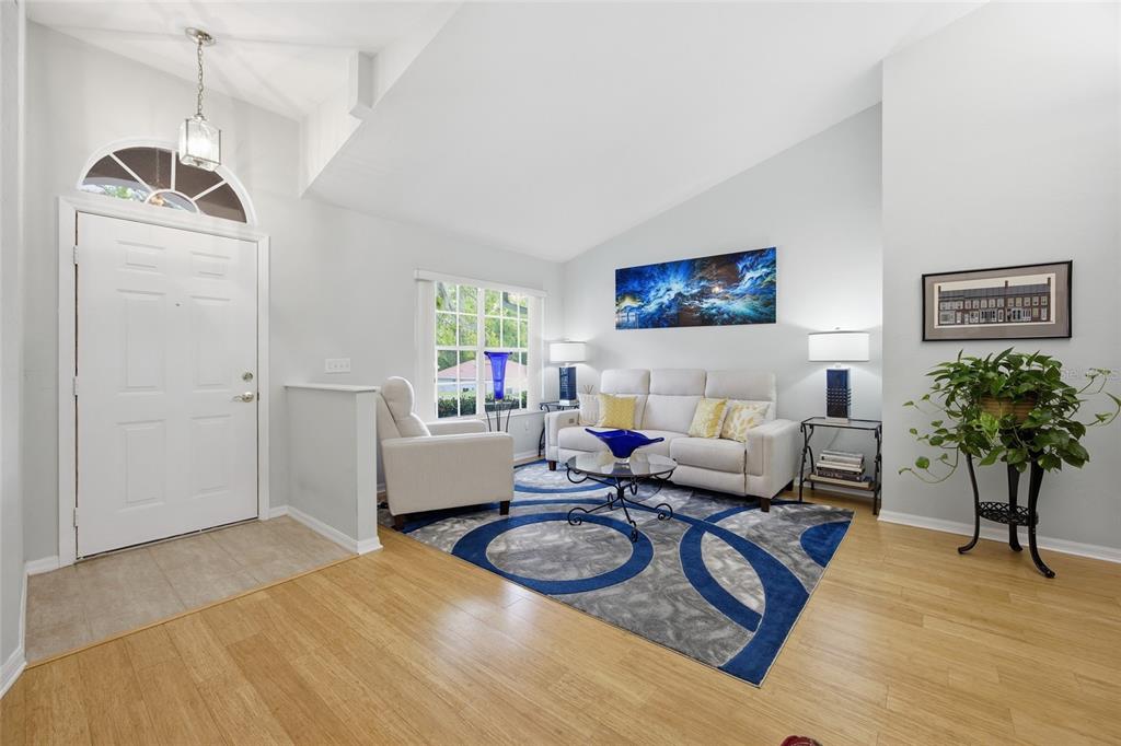 A bright living room features light wood floors, a white sofa, and a blue area rug — 1106 NW 101ST DRIVE, GAINESVILLE, FL