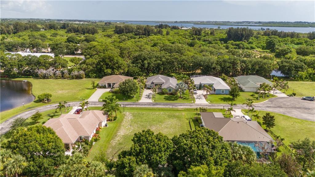 An aerial view shows several suburban houses with driveways and lawns near a wooded area — VERO BEACH, FL
