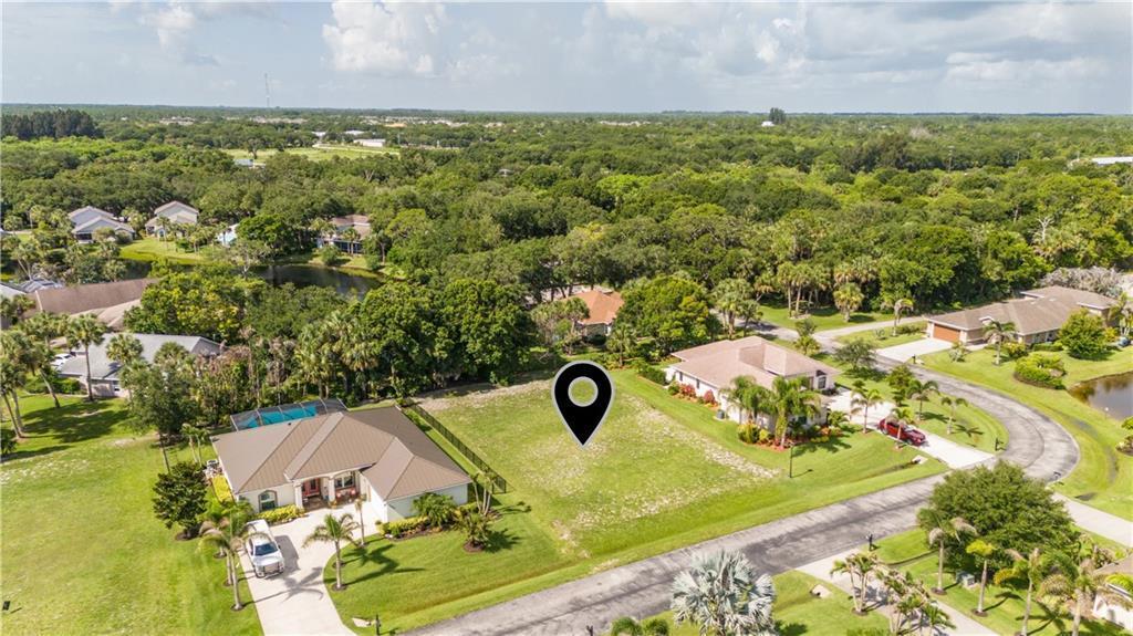 An aerial view shows a vacant residential lot situated between two single-family homes — VERO BEACH, FL