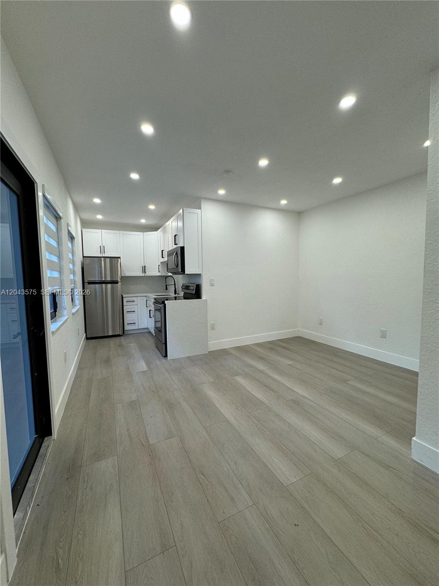 A modern kitchen with white cabinets and stainless steel appliances opens into a dining area — 5521 NW 1st Ave # 4, Miami FL 33127, MIAMI, FL