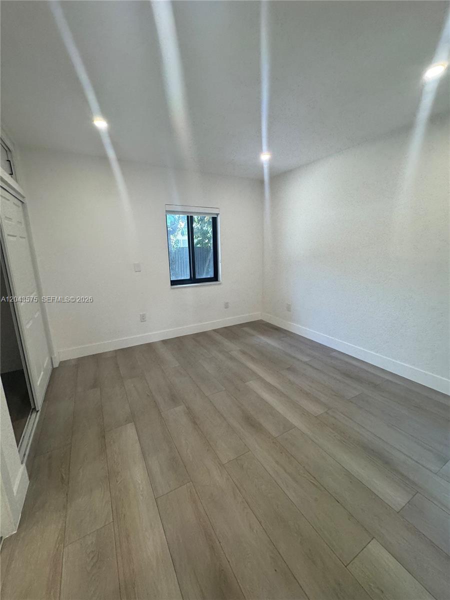 An empty room features light wood-look flooring, white walls, and a single window — 5521 NW 1st Ave # 4, Miami FL 33127, MIAMI, FL