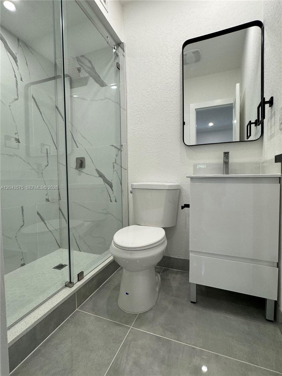 A modern bathroom features a glass-enclosed shower, a white vanity, and a black-framed mirror — 5521 NW 1st Ave # 4, Miami FL 33127, MIAMI, FL