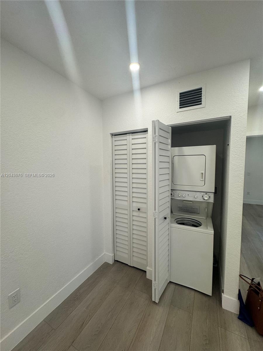 A laundry closet with a stacked washer and dryer sits in a room with wood-look flooring — 5521 NW 1st Ave # 4, Miami FL 33127, MIAMI, FL