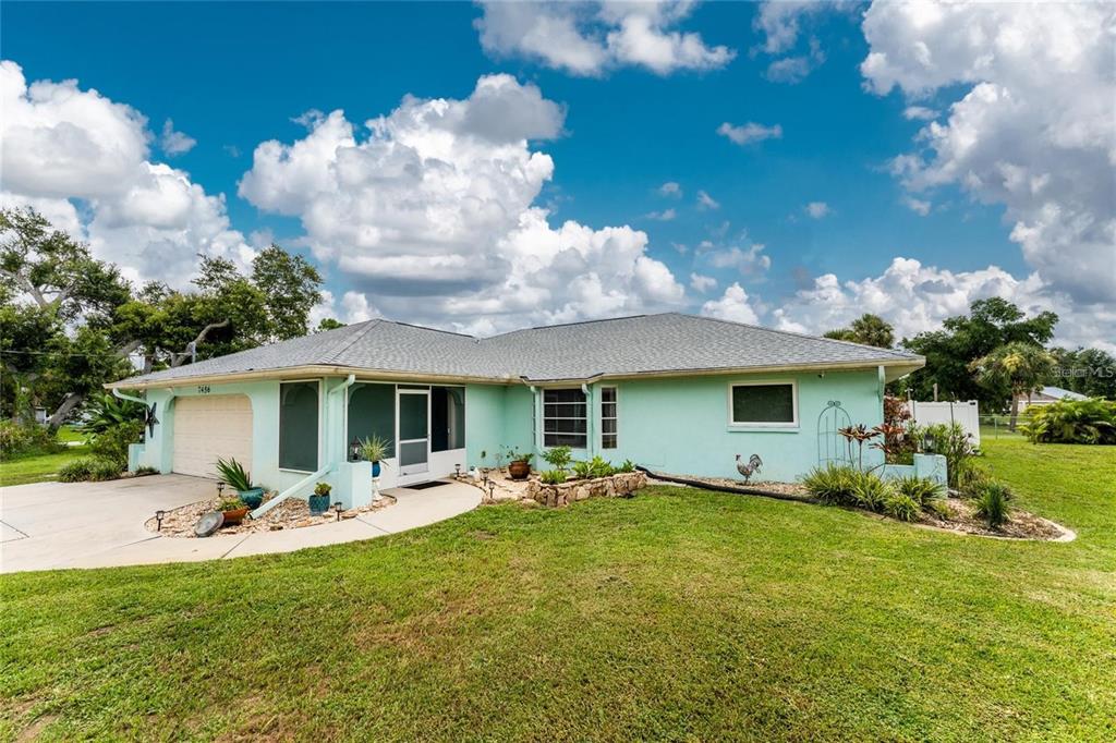 A light green single-story house with a two-car garage and a large grassy yard — 7456 JENNIFER DRIVE, PORT CHARLOTTE, FL