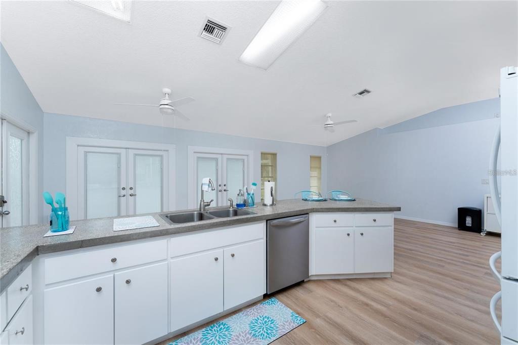 A kitchen with white cabinets, a gray countertop, a double sink, and light wood flooring — 7456 JENNIFER DRIVE, PORT CHARLOTTE, FL