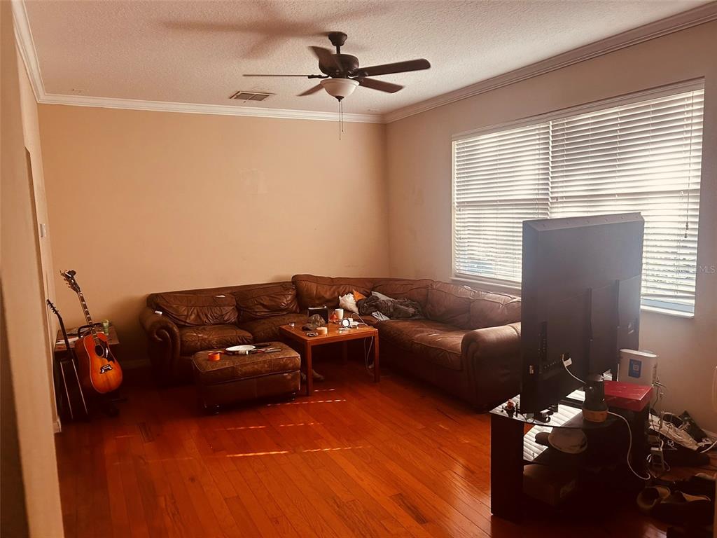 A living room features hardwood floors, a brown leather sectional sofa, and a ceiling fan — 9962 BENNINGTON CHASE DRIVE, ORLANDO, FL