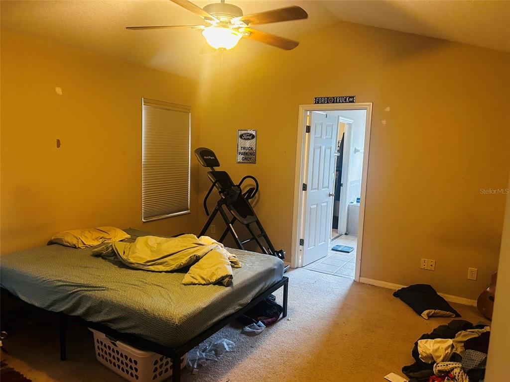 A bedroom with a bed, an inversion table, and a doorway leading to a bathroom — 9962 BENNINGTON CHASE DRIVE, ORLANDO, FL