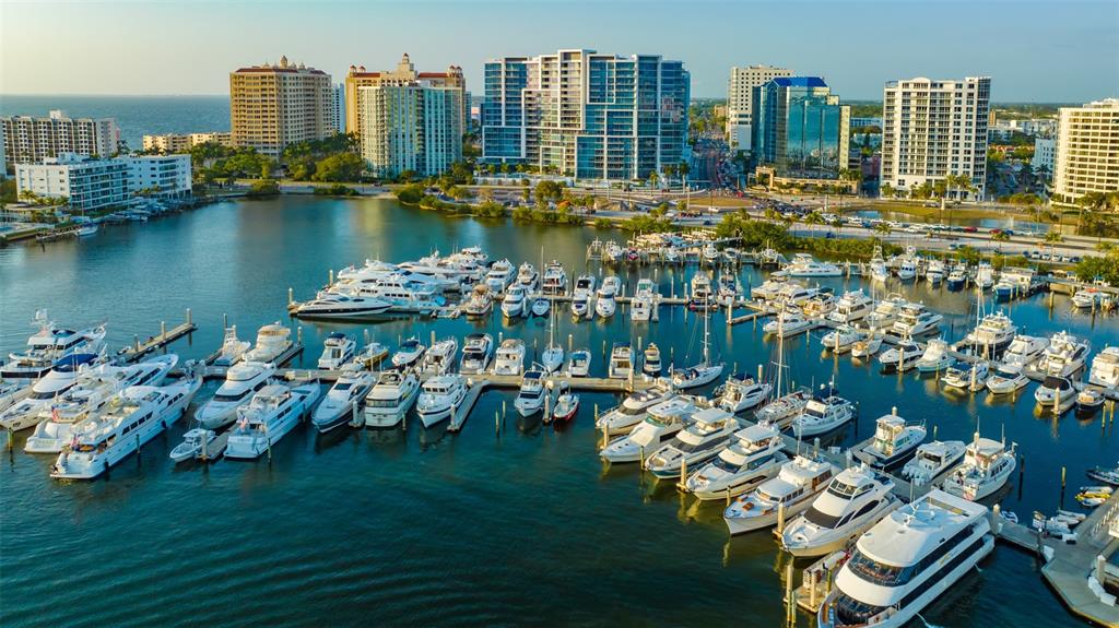 An aerial view of a marina filled with yachts in front of a coastal city — 1350 MAIN STREET UNIT 908, SARASOTA, FL
