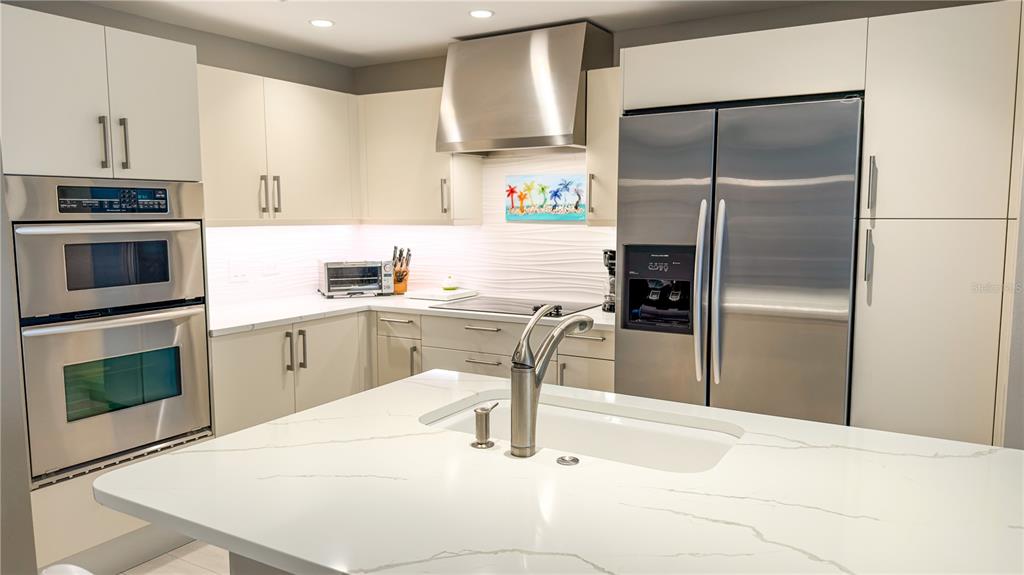 A modern kitchen features white cabinets, stainless steel appliances, and a white quartz island countertop — 1350 MAIN STREET UNIT 908, SARASOTA, FL