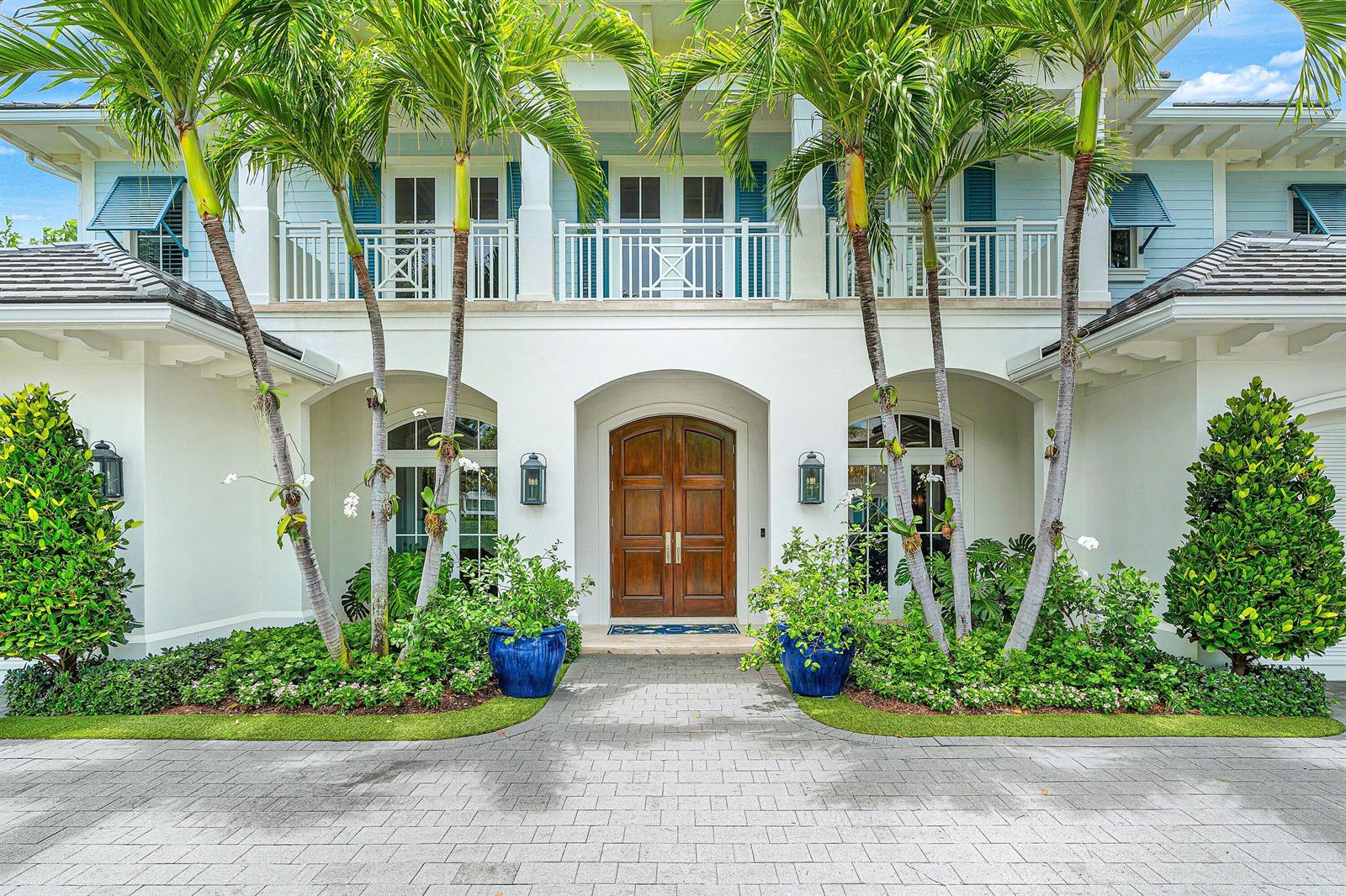 A two-story house with a white facade, arched entryway, wooden double doors, and palm trees — 2249 E Maya Palm Drive, Boca Raton FL 33432, BOCA RATON, FL