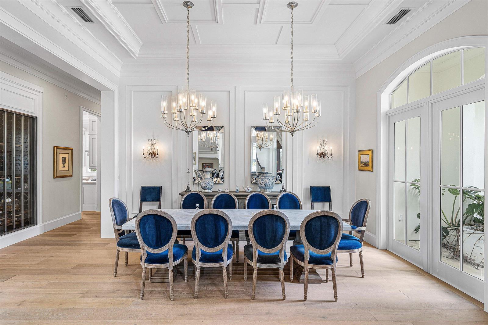 A formal dining room features a long marble table, blue velvet chairs, and two chandeliers — 2249 E Maya Palm Drive, Boca Raton FL 33432, BOCA RATON, FL