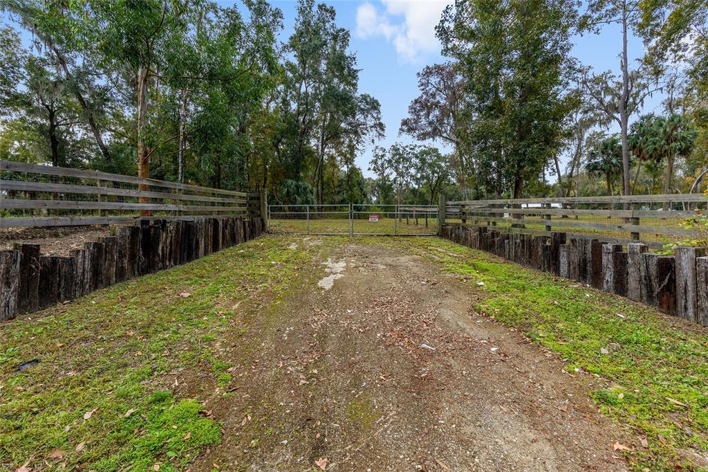 A large, grassy field features several mature trees and a metal barn with red doors — 2578 SE 110TH STREET, OCALA, FL