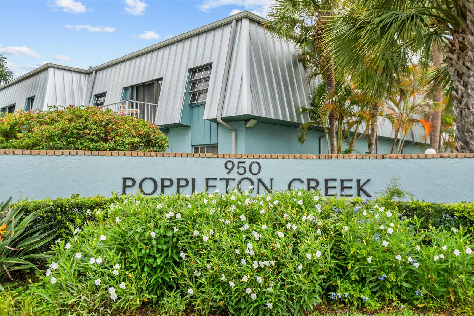The exterior of a light blue building with a metal roof sits behind a sign — 950 S Kanner Highway # 402, Stuart FL 34994, STUART, FL