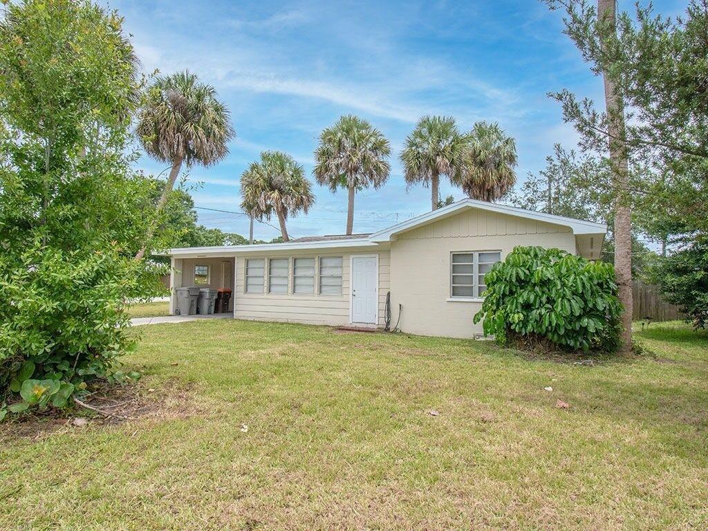 A single-story house with light siding, a carport, and palm trees in the yard — VERO BEACH, FL